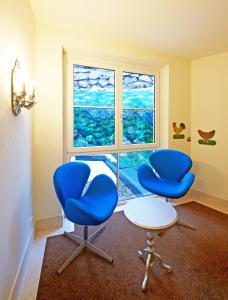 two blue chairs and a table in a room with a window at Hotel Saalbacher Hof in Saalbach-Hinterglemm
