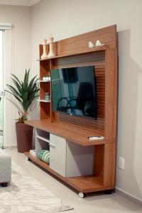 un centro de entretenimiento de madera con TV en la sala de estar en Apartamento Refúgio das Thermas, en Piratuba