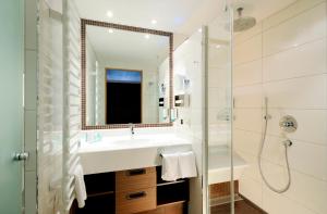 a bathroom with a sink and a shower and a mirror at Hotel Saalbacher Hof in Saalbach-Hinterglemm