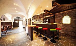 a bar in a restaurant with red and green stools at Hotel Saalbacher Hof in Saalbach-Hinterglemm