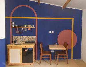 uma cozinha com uma mesa e uma parede azul em Suíte Central em Lençóis