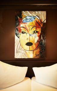a painting of a face on a wall above a bed at Hotel Saalbacher Hof in Saalbach-Hinterglemm
