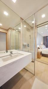 uma casa de banho com um lavatório, um chuveiro e uma cama. em Skybay Hotel Gyeongpo em Gangneung