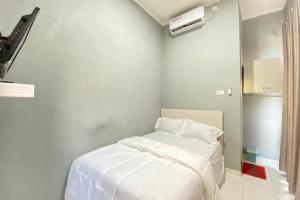 a white bedroom with a bed with white sheets at Pelangi Guest House Palembang RedPartner in Talang Kelapa
