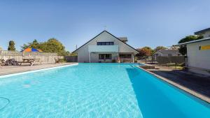 a large blue swimming pool in front of a house at Holdens Bay Holiday Park in Rotorua