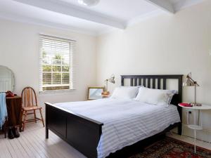 a bedroom with a large bed and a chair at Garden Cottage in Tea Gardens