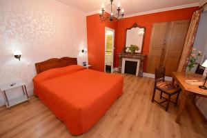 a bedroom with an orange bed and a desk at Hôtel De La Ferté in Chagny