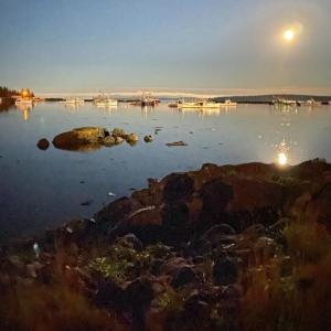 una luna che si innalza su un corpo d'acqua con barche di Harbor House Hotel by Umaniii in Jonesport Maine a Jonesport