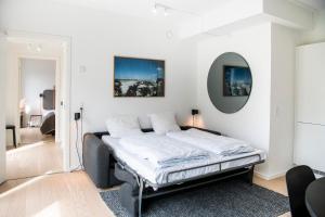 a white bedroom with a bed with a mirror at The Beach Gardens by Daniel&Jacob's in Copenhagen