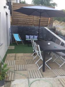 eine Terrasse mit einem Tisch, Stühlen und einem Sonnenschirm in der Unterkunft Maison cosy au calme in La Colle-sur-Loup