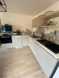 a kitchen with white cabinets and a wooden floor at Maison cosy au calme in La Colle-sur-Loup