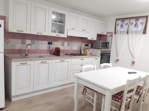 una cucina con armadi bianchi e tavolo bianco di Appartamento di Andrea a Teulada
