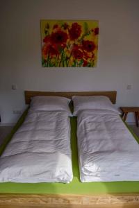 a bed with two white sheets and a painting on the wall at Chalet Seebauer in Neunburg vorm Wald