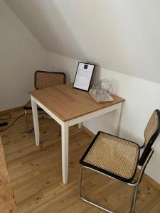 a wooden table with two chairs and a laptop on it at ApartMENTZ - 3 Zimmer Apartmenthaus in Sankt Peter ob Judenburg