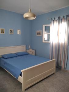 a blue bedroom with a bed and a window at Myconian Cottage in Ano Mera