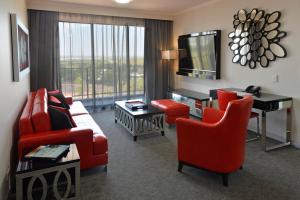 a living room with red furniture and a large window at Rydges Palmerston - Darwin in Darwin