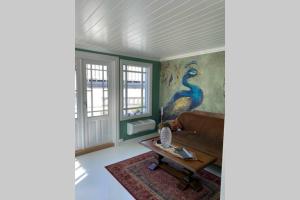 una sala de estar con sofá y una pintura de pavo real en Huset ved evja, en Ulefoss