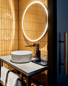 a bathroom with a sink and a round mirror at Karl August - a Neighborhood Hotel in Nürnberg