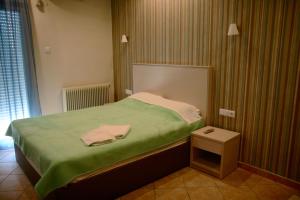 a small bedroom with a bed with a green blanket at Margarita's Rooms in Potos