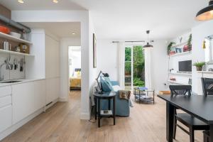 a kitchen and dining room with white cabinets and a table at JOIVY Stylish 2-bed flat with garden in Notting Hill in London