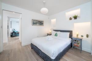 ein Schlafzimmer mit einem großen weißen Bett in einem Zimmer in der Unterkunft JOIVY Stylish 2-bed flat with garden in Notting Hill in London
