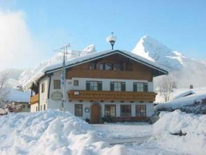 a large building with a snow covered mountain in the background at Gästehaus Watzmannblick in Bischofswiesen