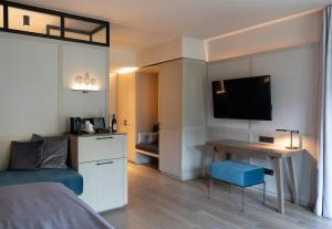 a bedroom with a bed and a desk with a television at Parkhotel Egerner Höfe in Rottach-Egern
