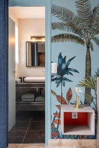 a bathroom with a painting of a palm tree on the wall at Une Escale à Pornic chambres d'hôtes 4 épis in Pornic