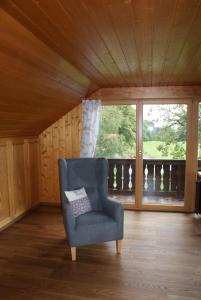 une chaise bleue dans une chambre avec fenêtre dans l'établissement Ferienwohnung Weber, à Habach