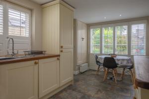 a kitchen with a sink and a table with chairs at Sage Cottage in Atworth