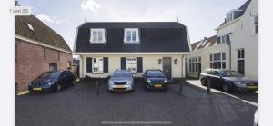 three cars parked in a parking lot in front of a house at Appartement Warmond in Warmond