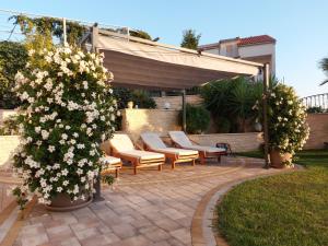 a patio with chairs and a bush with white flowers at Villa Principessa Podstrana in Podstrana