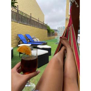 a woman laying on a hammock with a glass of wine at Casa Miradouro do Moinho in Porto Santo