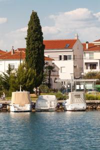 tres barcos están atracados en el agua cerca de edificios en Beach Apartments Rafael, en Zadar