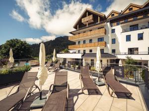 eine Reihe von Stühlen und Sonnenschirmen auf dem Balkon eines Hotels in der Unterkunft Alpenheimat Laurschhof in Fiss