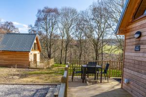a patio with a table and chairs and a cabin at Thistle Lodge 20 with Hot Tub in Belladrum