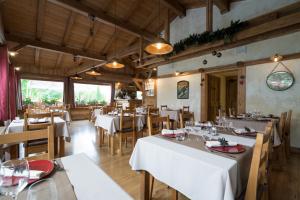 un restaurante con mesas blancas y sillas de madera en La Ferme Du Lac en Thyez