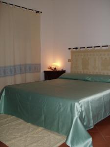 1 dormitorio con 2 camas y colcha verde en Rocca Ruja Vip, en Stintino