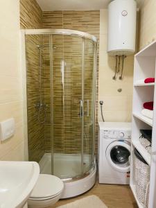 a bathroom with a shower and a toilet and a washing machine at Apartman M&M in Doboj