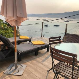 a patio with a table and chairs and an umbrella at Villa Balbina in Bueu