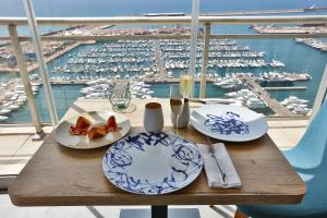 een houten tafel met borden eten en uitzicht op een haven bij Hotel Alicante Gran Sol, affiliated by Meliá in Alicante