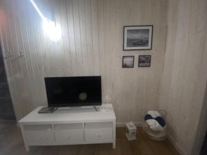 telewizor siedzący na białej szafce w pokoju w obiekcie Domek Morze w Ustce
