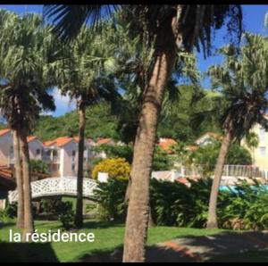 un grupo de palmeras en un patio con las palabras "la residencia" en APPARTEMENT T2 ROUTE DES SALINES, en Sainte-Anne