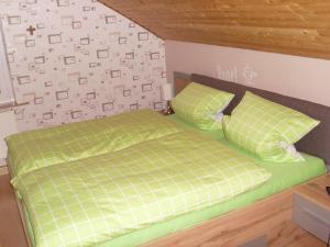 a bedroom with a green bed and two pillows at Ferienwohnung am Waldrand in Schmallenberg