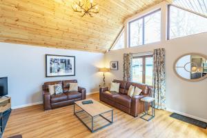 a living room with leather furniture and a wooden ceiling at Thistle Lodge 22 with Hot Tub in Belladrum
