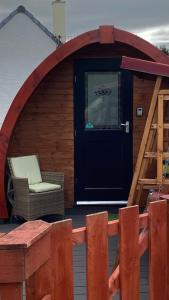 a gazebo with a chair and a door at Heatherbrae Cosy Wooden Pod in Kyle of Lochalsh
