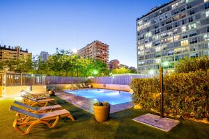 uma piscina com espreguiçadeiras e um edifício em Hotel Valencia Oceanic Affiliated by Meliá em Valência