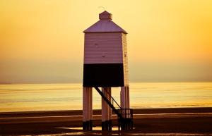 a lighthouse on the beach with the ocean in the background at Seashell luxury apartment in Burnham on Sea