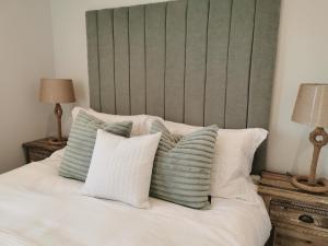 a bed with a green headboard and white pillows at Seashell luxury apartment in Burnham on Sea