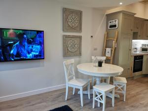 a kitchen with a table and chairs and a tv on the wall at Seashell luxury apartment in Burnham on Sea